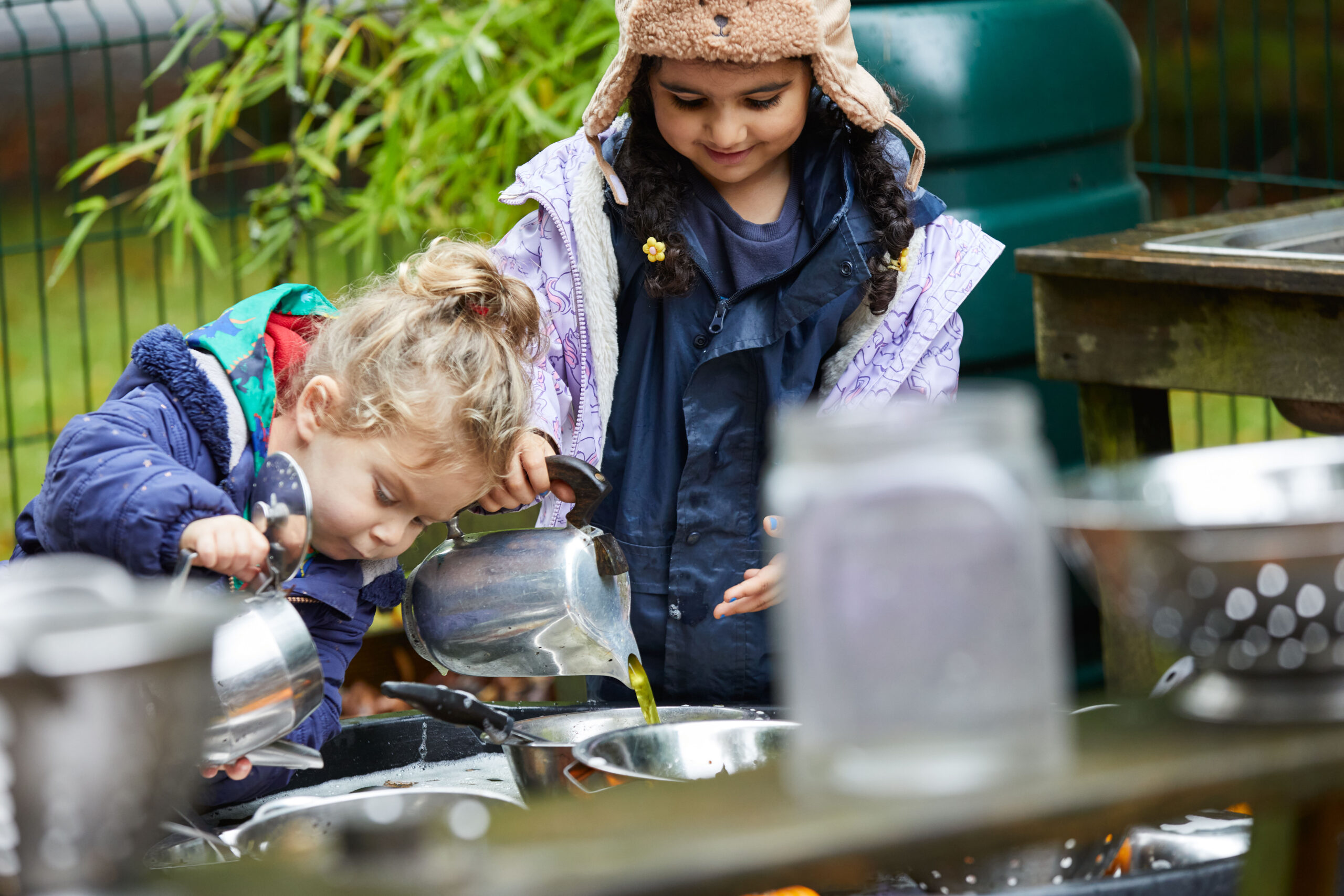 2 small children playing in the nursery garden on a water table