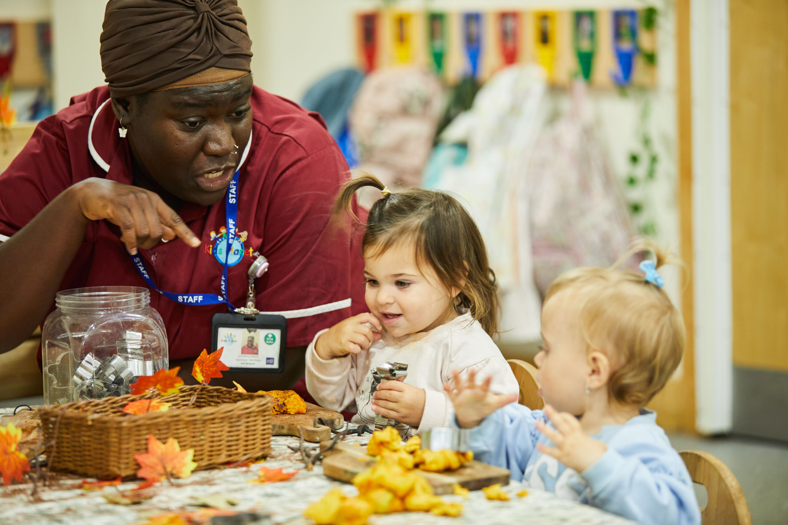 a nursery staff member and 2 infants sat at the dining table