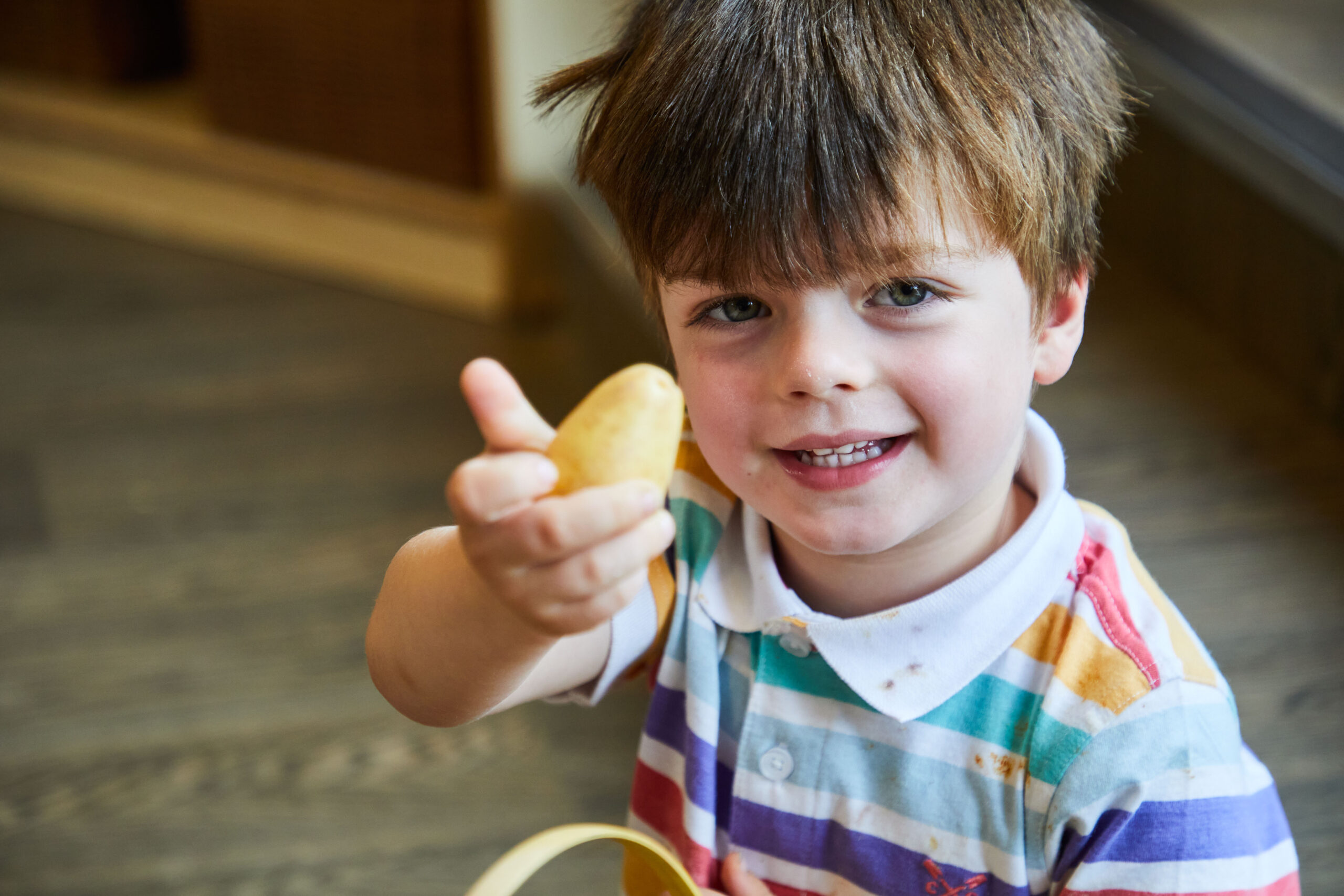 a nursery child holding some vegetables and smiling