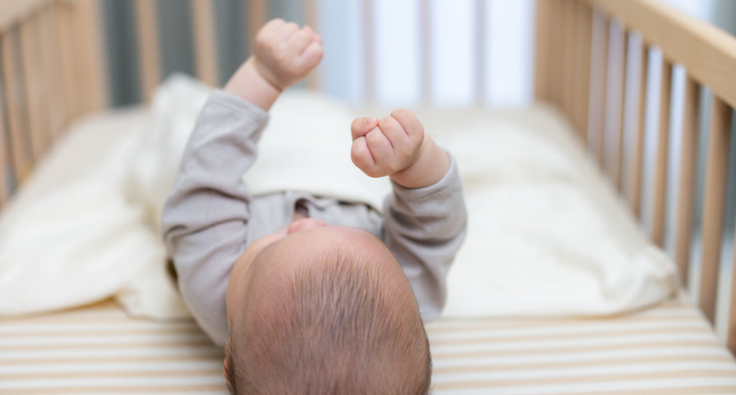 an image of a baby laying on their back in a cot