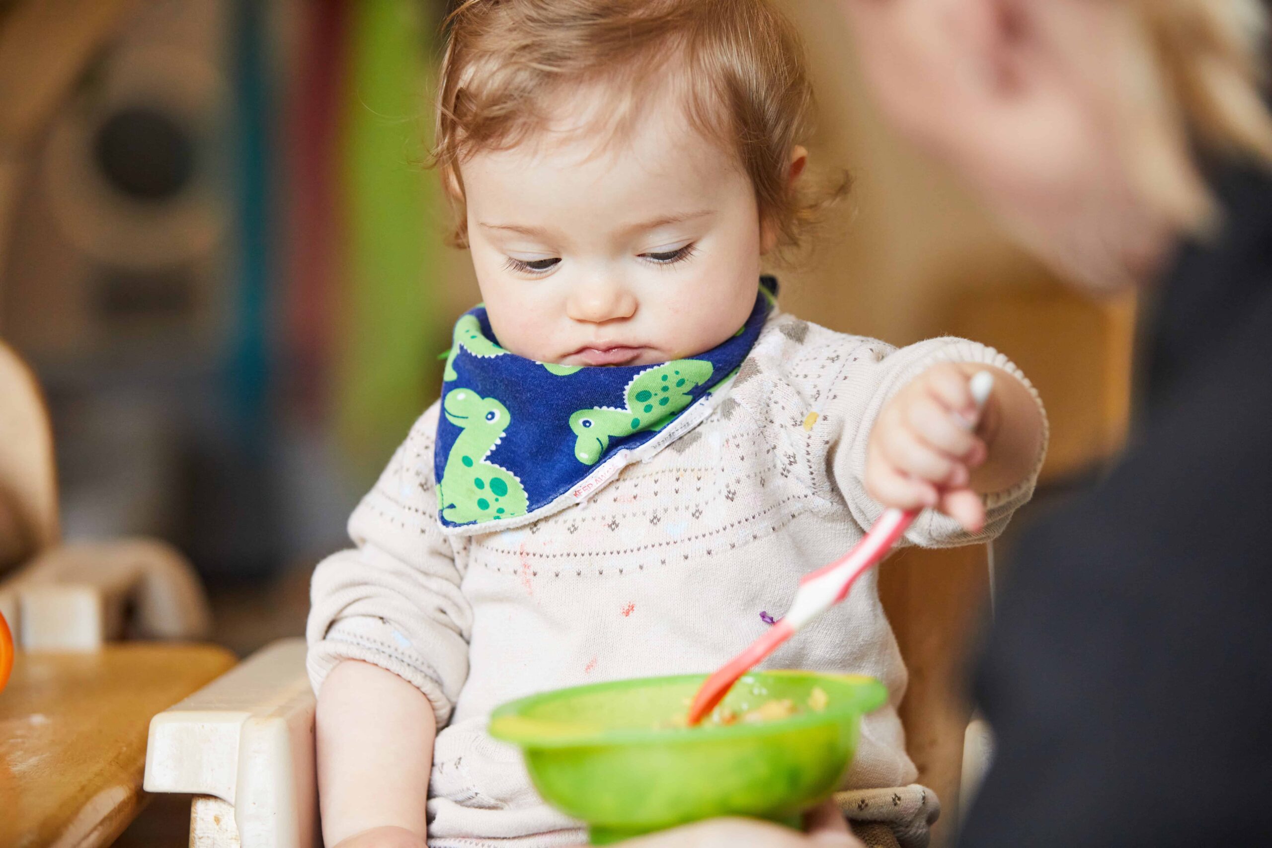 image of an infant with a bowl of food and wearing a bib at mealtime