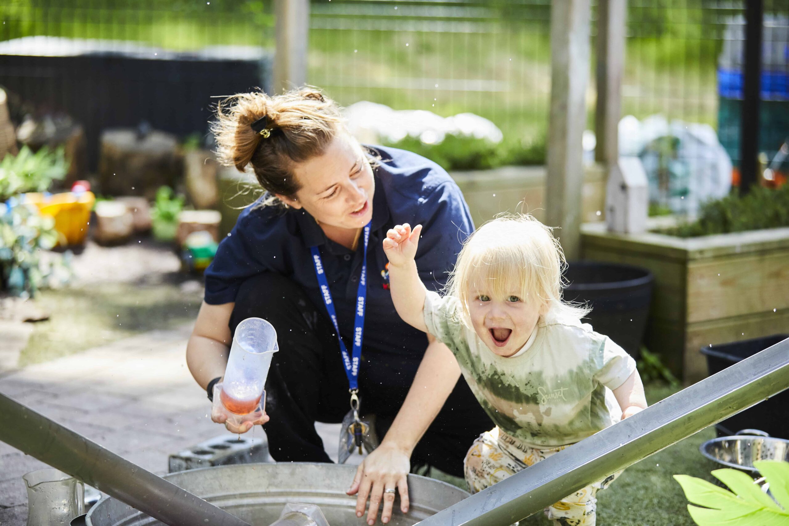 image of a toddler and a nursery staff member playing outside