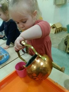 Child pouring real tea from a teapot