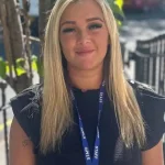 Blonde woman wearing a blue lanyard reading 